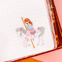 Load image into Gallery viewer, sticker of girl riding a carousel horse in a notebook